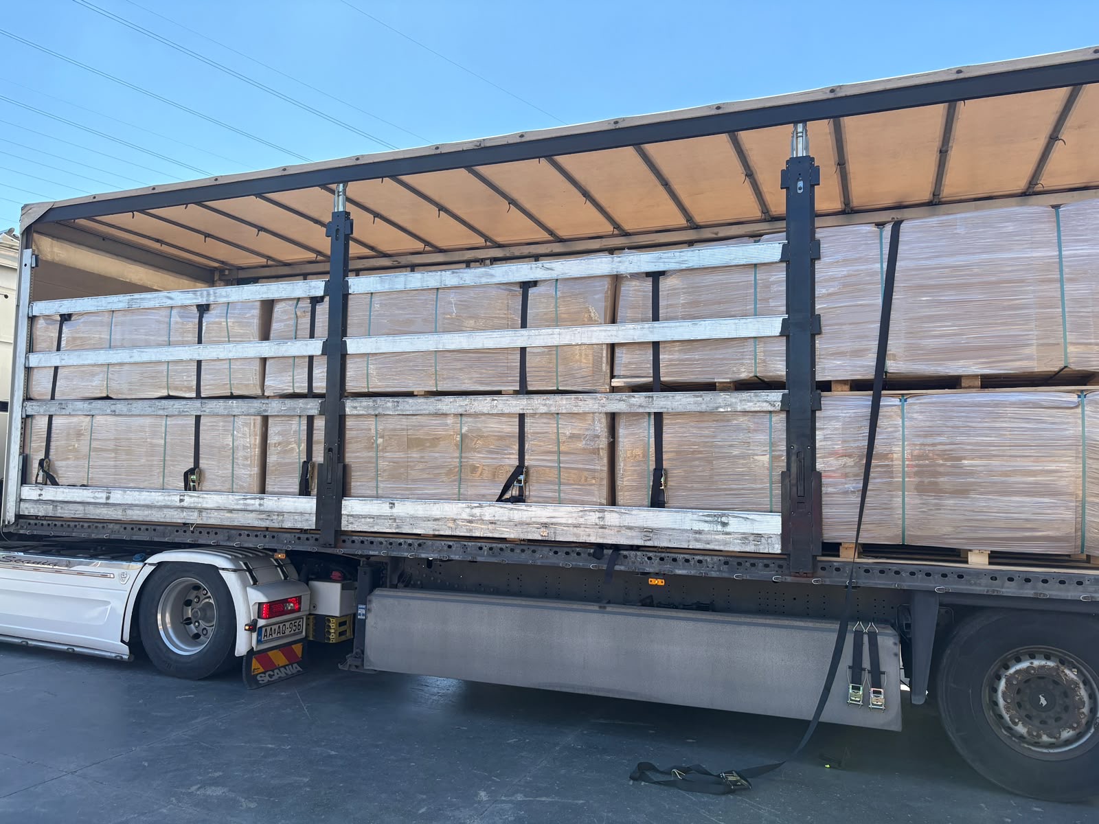 Curtain-side lorry fully loaded with wholesale acoustic panel pallets on a sunny dispatch day